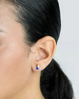 Close-up of an ear wearing a colorful earring with a plain background