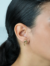 Close-up of a person wearing a gold hoop earring with a light blue background