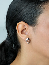 Close-up of an ear wearing a silver hoop earring with a blurred background