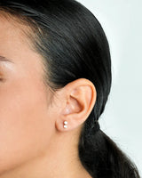 Close-up of an ear with a small earring against a neutral background