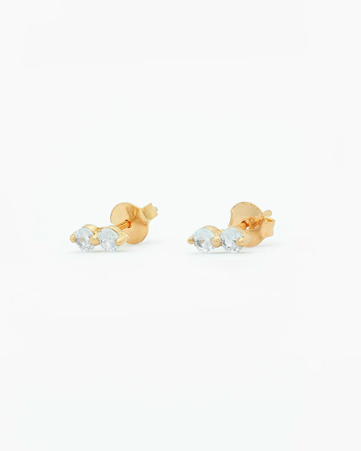 Gold earrings with clear gemstones on a white background