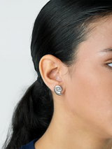 Close-up of a person wearing a spiral earring on a plain background