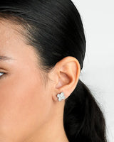 Close-up of an ear wearing a silver butterfly earring with a blurred background