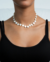 Pearl necklace worn by a person against a light background