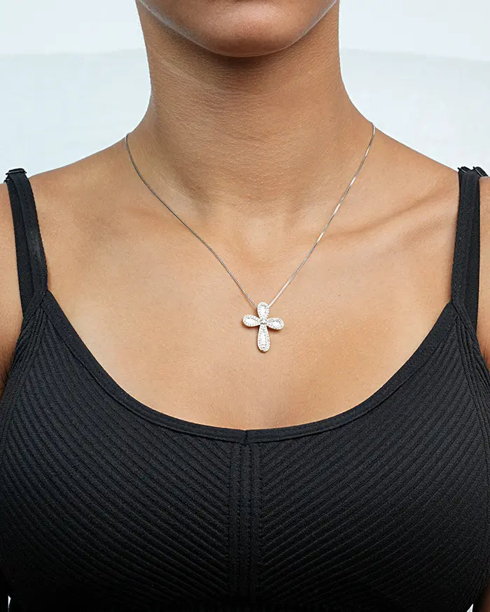 Person wearing a black tank top with a silver necklace featuring a cross pendant.