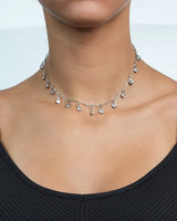 Necklace with small pendants on a person wearing a black top against a light background